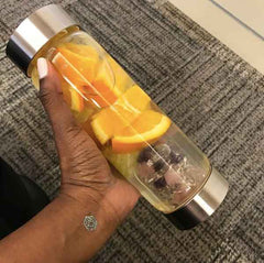Sharon Jackson wearing a teal love intention and mindfulness tattoo while holding a water filled with orange slices.