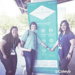 LumenKind Event setup with three ladies showing off their Mindful Mark temporary tattoos in front of banner.