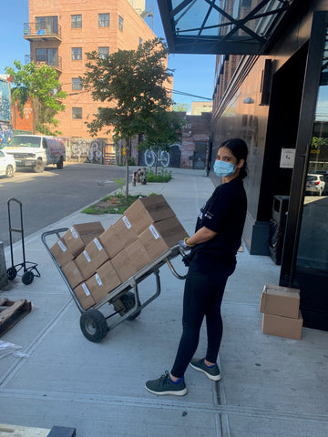 Boxes on a hand cart being moved by a woman