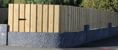 board and batten fence sitting on retaining wall