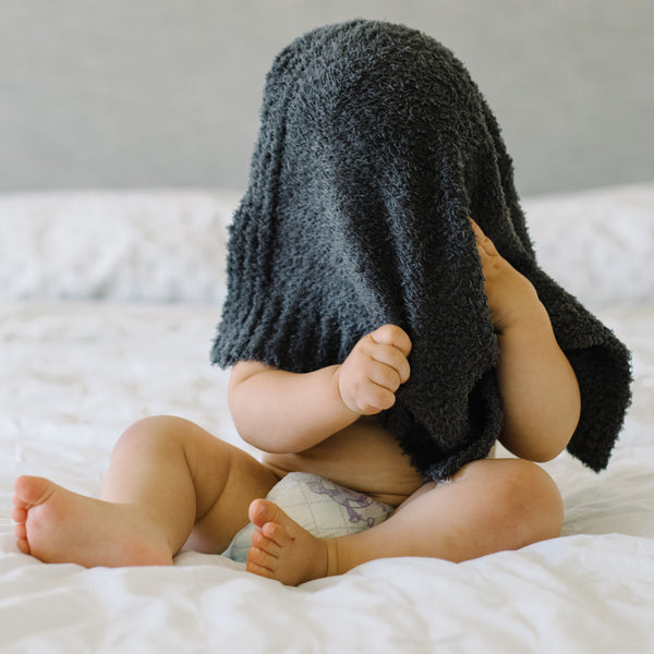 An infant is playfully grasping a luxury bamboo Saranoni bamboo mini security blanket. 