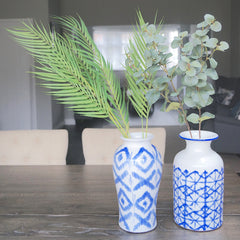 Fake palm leaves and eucalyptus leaves in large blue and white vases