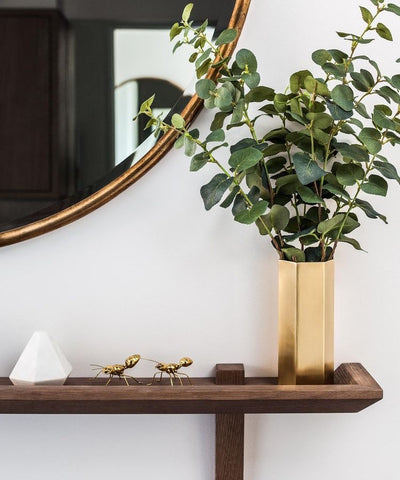 Polished brass vase with greenery, wooden console table, large round brass mirror styled by Gordon-Duff & Linton