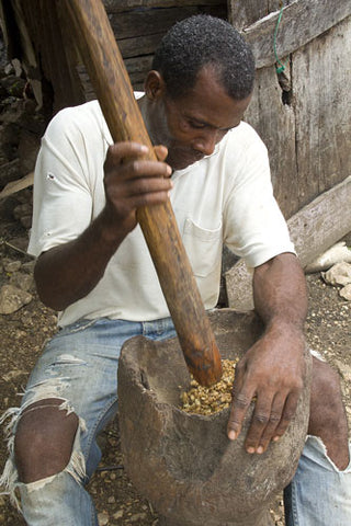Mann in traditioneller Kaffeerösterei in der dominikanischen Republik stampft den Kaffee