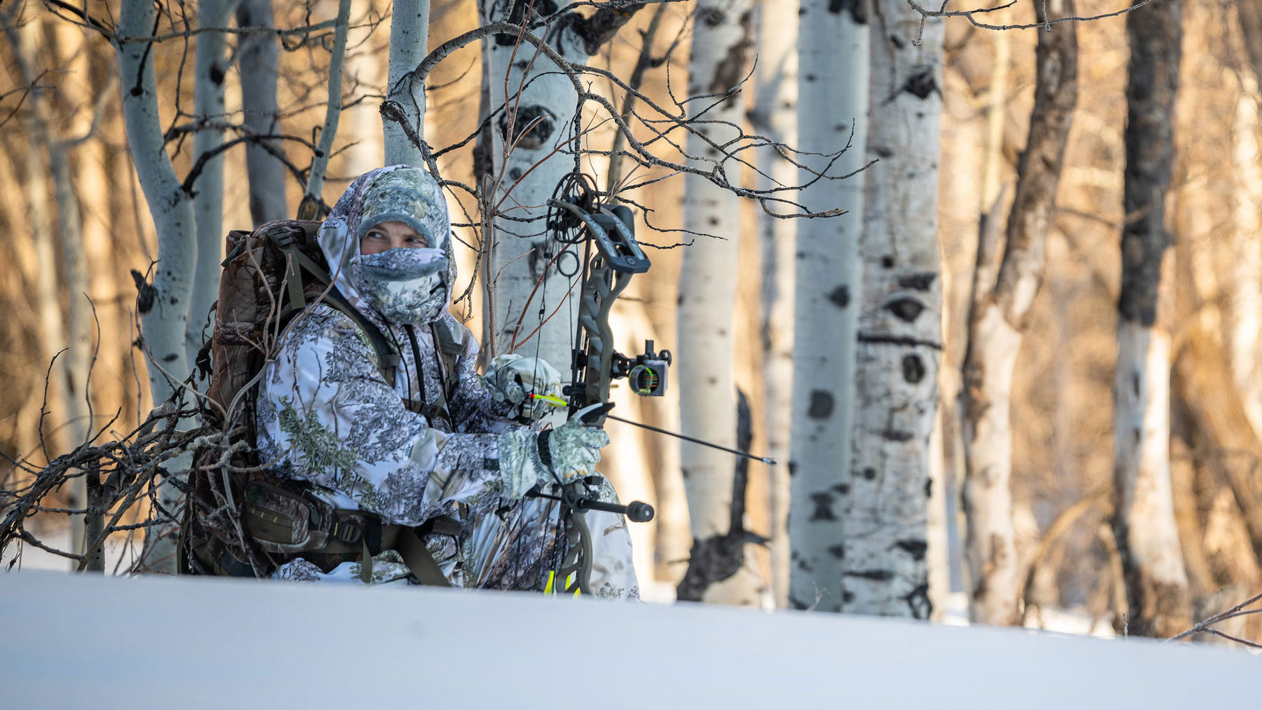 man wearing snow camo and holding bow