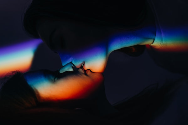 two women kissing in rainbow light