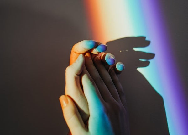 holding hands in rainbow light