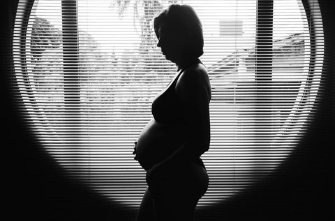 Pregnant in front of blinds