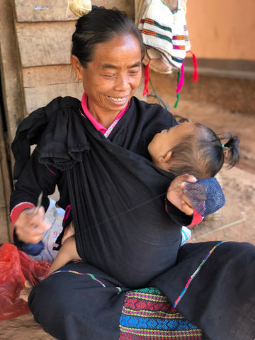 khmu artisan works while nurturing her child 