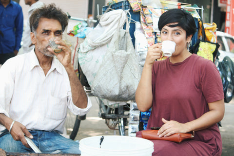 Man and woman sitting in a street in India drinking chai