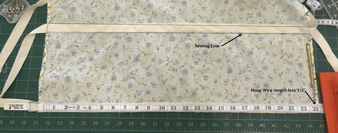 Along the bottom edge on the right side of the fabric, align the bottom of a 1 ½ yard piece of twill tape with the top of the serging and align the center of the tape with the center of the fabric.  Sew the bottom edge of the twill tape down 1/8” from the edge of the twill tape. Step 8