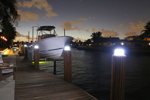 A boat docked on water in front of portable solar lights on the dock