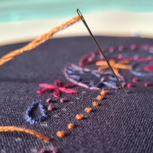 a photo of an embroidery needle poking through an embroidery design