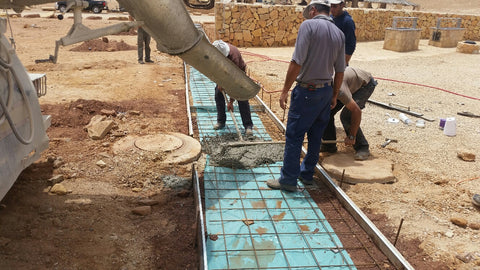 Construction workers pouring concrete for a glowing concrete pathway.