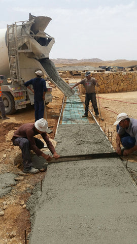Construction workers troweling concrete for a glowing concrete pathway.