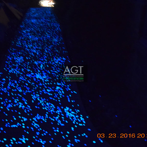 Concrete walkway powered by 1/2" (12-14mm) AGT™ Commercial-Grade Glow in the dark gravel in Aqua Blue and Emerald Yellow glow colors. Night time.