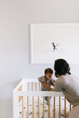 postpartum woman holding baby in crib