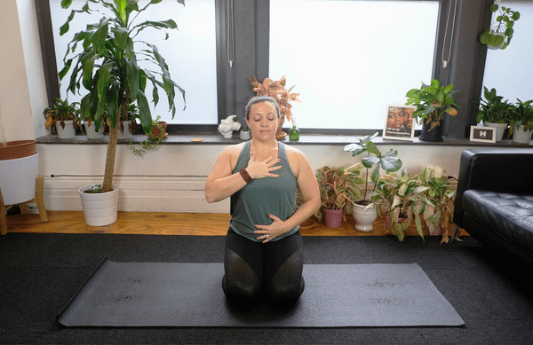 Kate demonstrating focused breathing with hand on chest and belly 