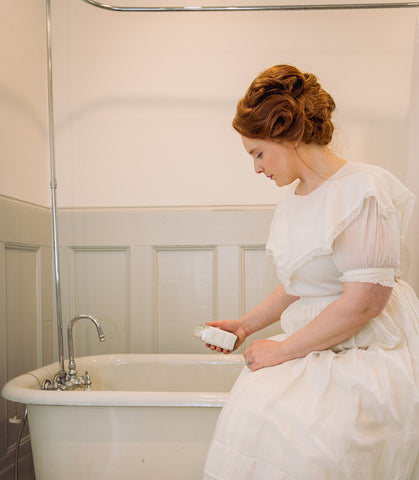 Victorian woman pouring Willow & Birch Apothecary bath salts into antique tub