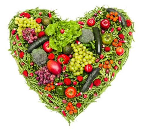 A collection of fresh fruits and veggies placed in a heart shape.