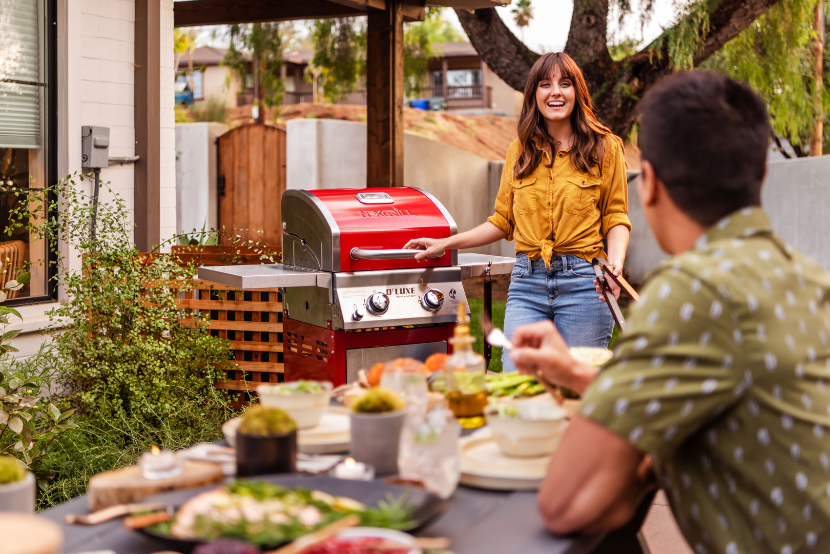 young couple grilling on their Nexgrill DEluxe 2-burner red gas grill