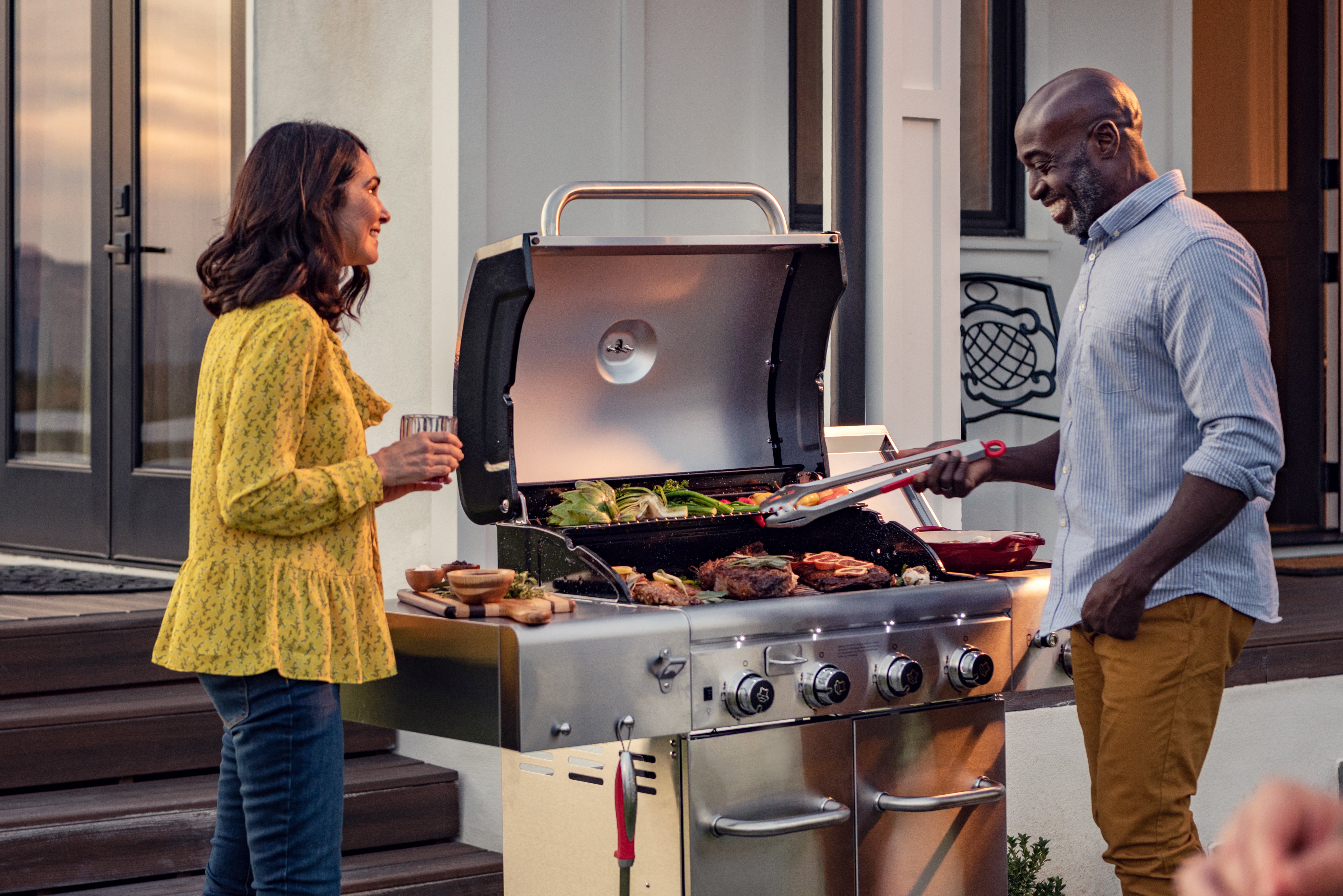 man and woman grilling on the nexgrill revelry 4-burner gas grill