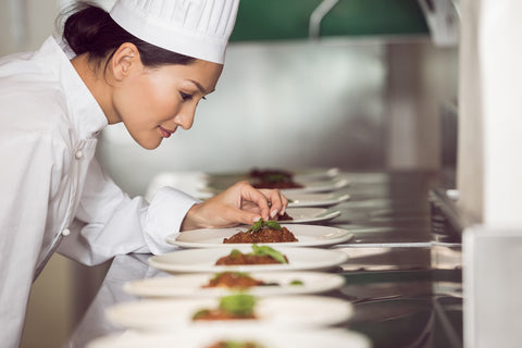 female chef preparing food on the expo line at restaurant