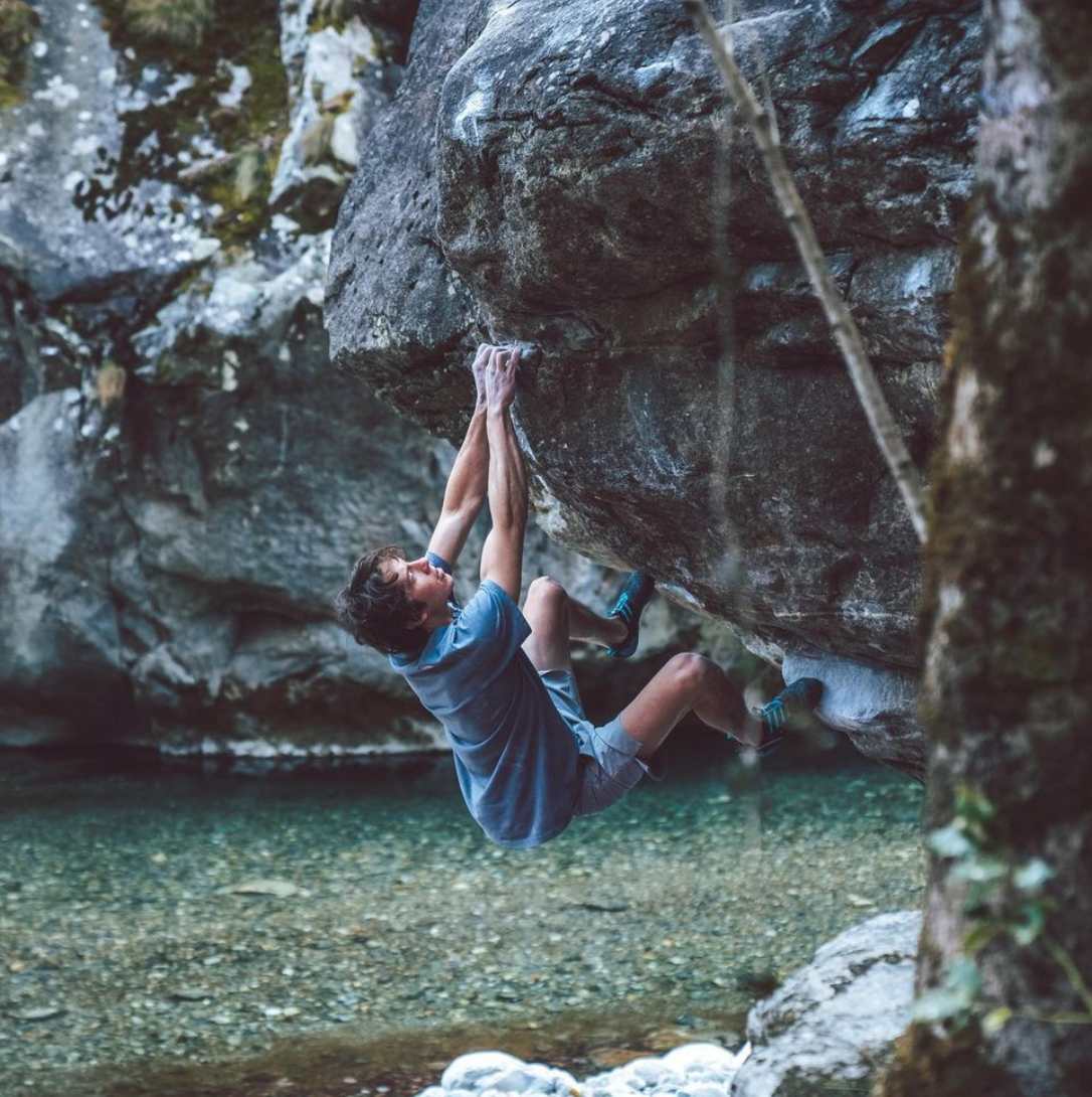 matty hanging onto a rock with a pretty lake in the background