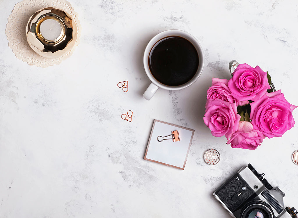 Flat lay of coffee, flowers, camera, candles and stationary items