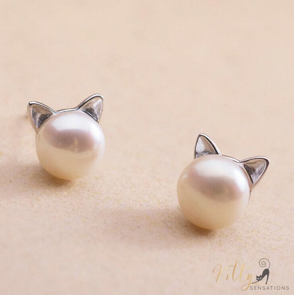 silver cat earrings with a freshwater pearl on light brown surface