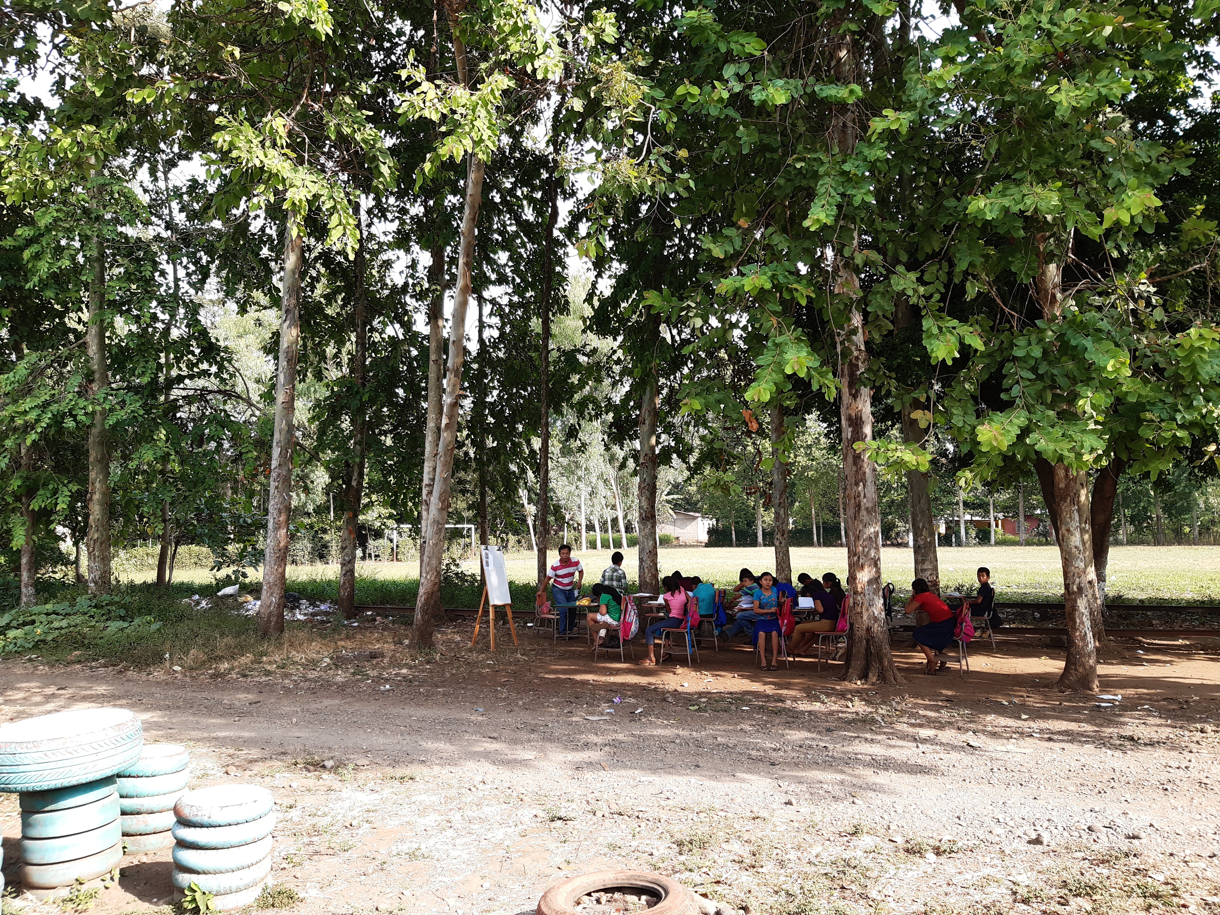 children at desks in an outdoor classroom