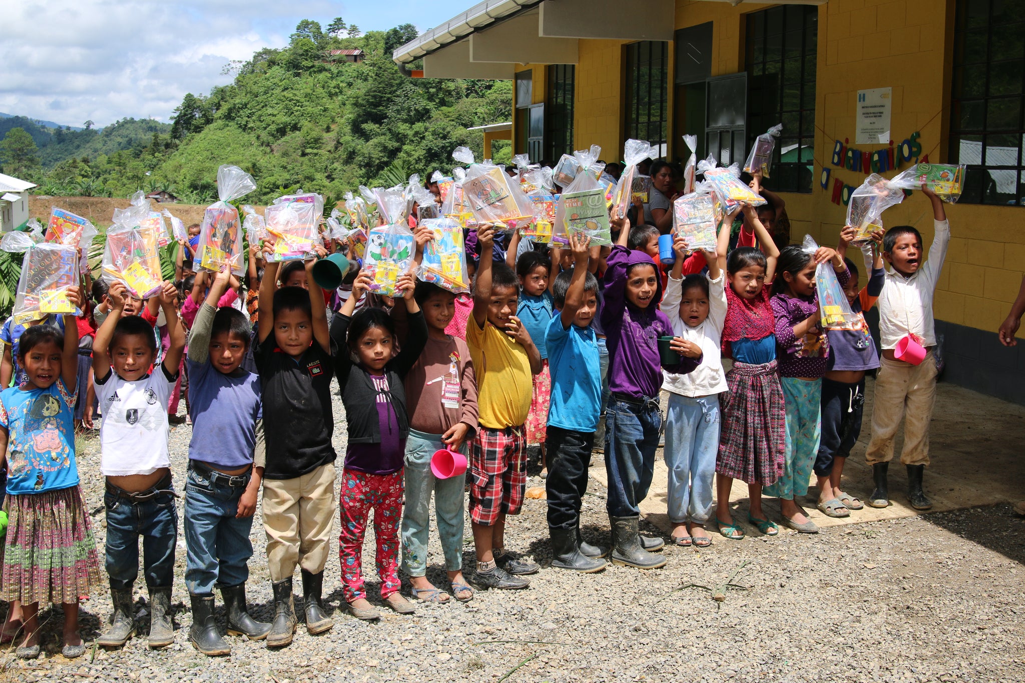children happily holding up their bags of school supplies