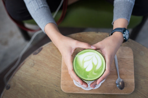 a cup of matcha green held by two hands