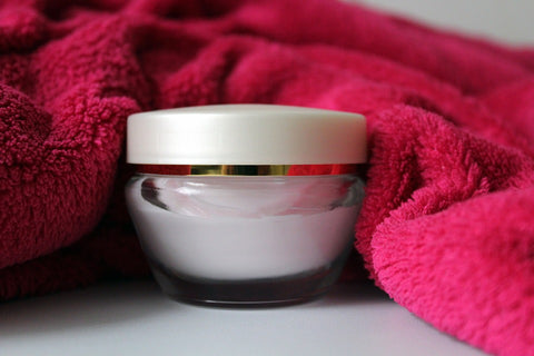cream in a jar beside a pink towel