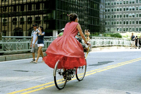A photo of a woman in a puffy layered red dress on a bike taken by Bill Cunningham in NY.
