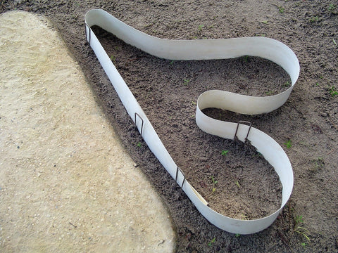 Square top landscape staples used to support a divider in a garden