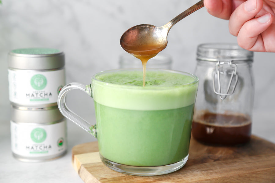 Honey being poured over a warm matcha latte