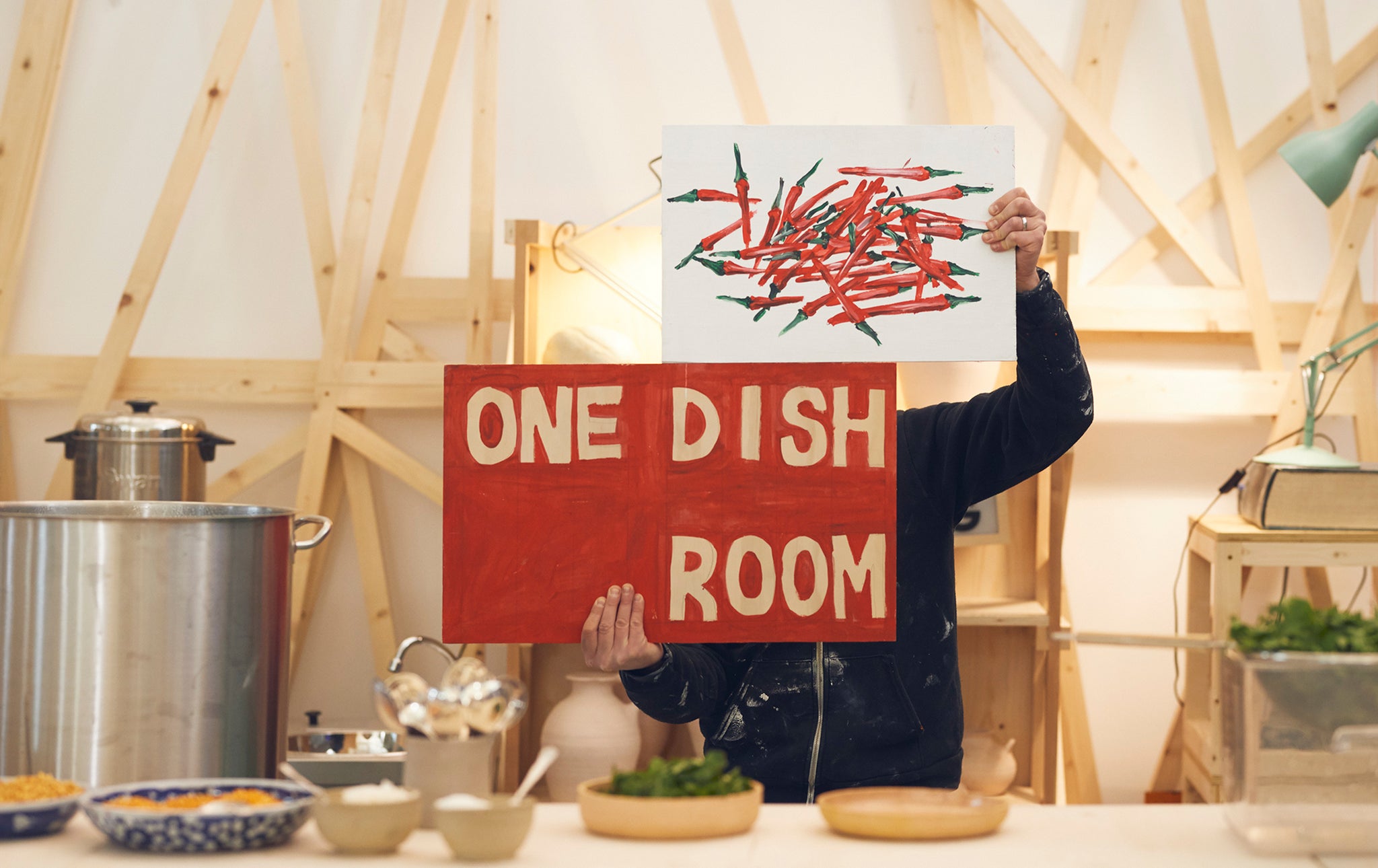 Ben holding up a sign saying One Dish Room for his Dhal project