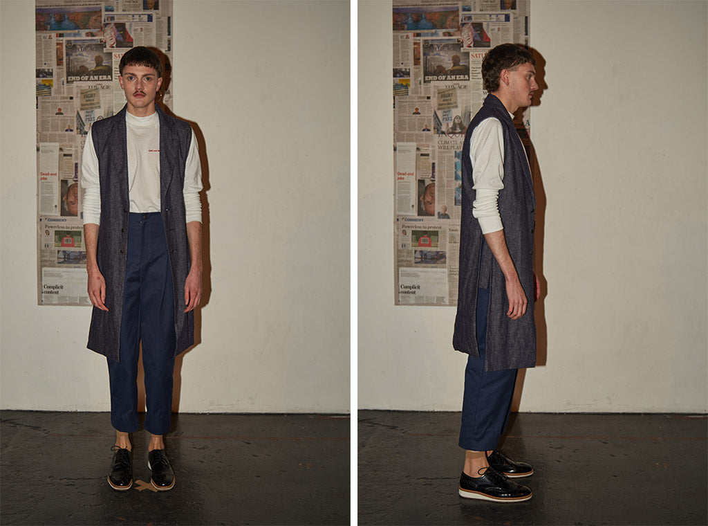 Tailored navy trousers paired with long-sleeve white cotton turtle neck top and sleeveless long denim waistcoat