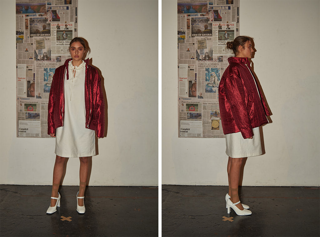 Mid-length dress with high ruffle neckline paired with limited edition metallic red bomber jacket