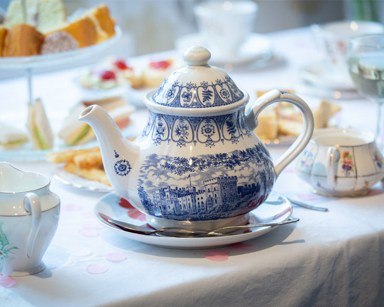 The tea pot and cakes from my mums tea party. Set on a white table cloth with a blue and white tea pot.
