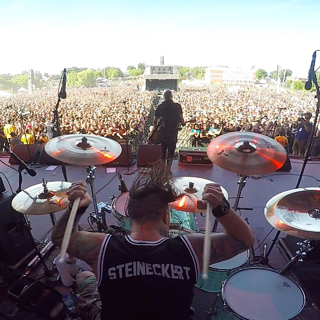 Brandon Steineckert playing drums in the band Rancid in front of a giant crowd.