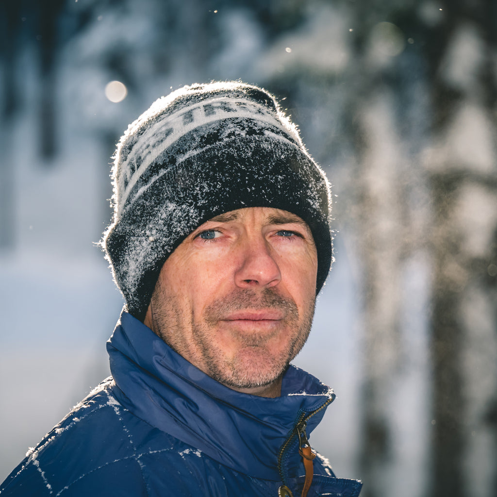 Jeremy Jones portrait wearing a beanie with snow falling.