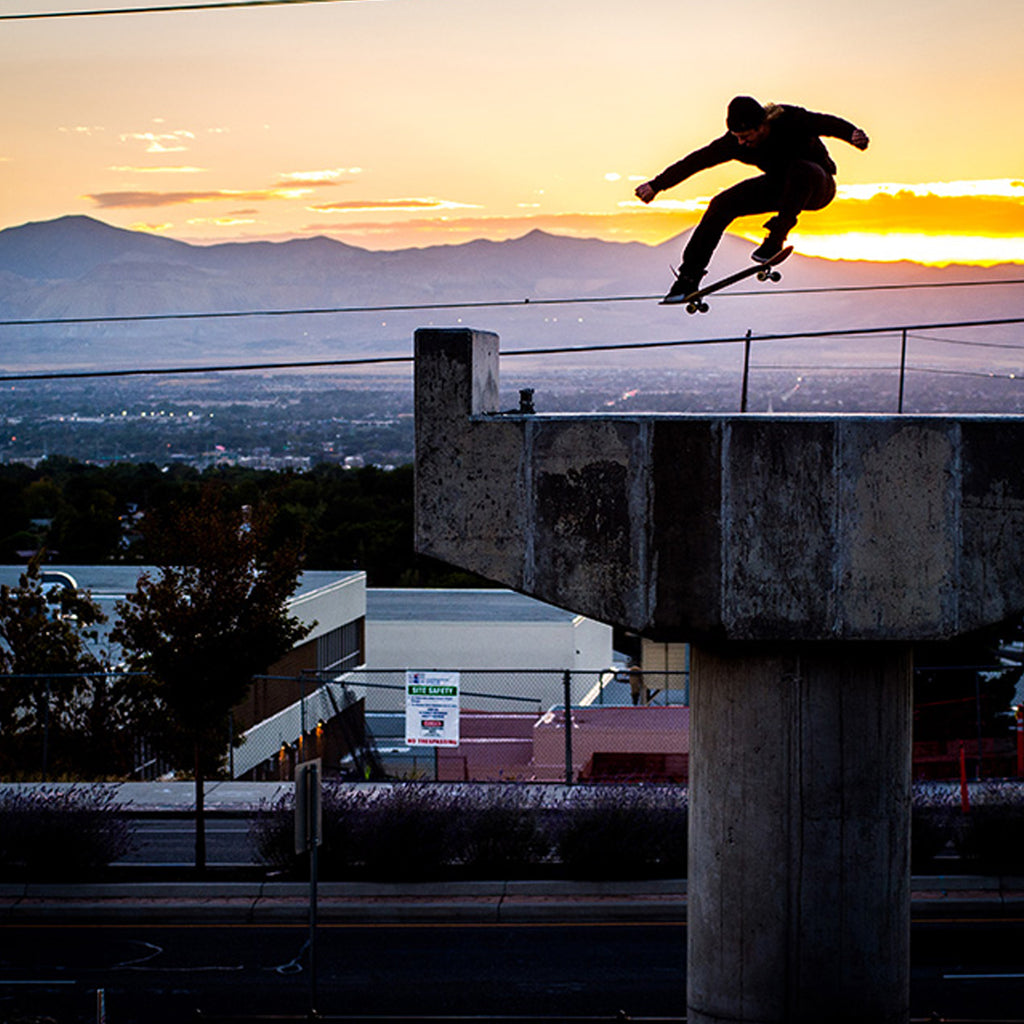 Jeremy Jones doing an ollie over a handrail on his skateboard with a sunset in the background.