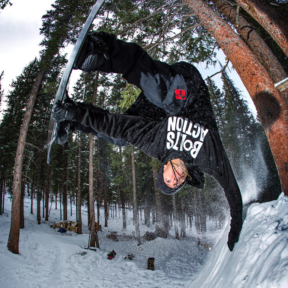 Jeremy Jones doing a hand plant on his snowboard in the woods.