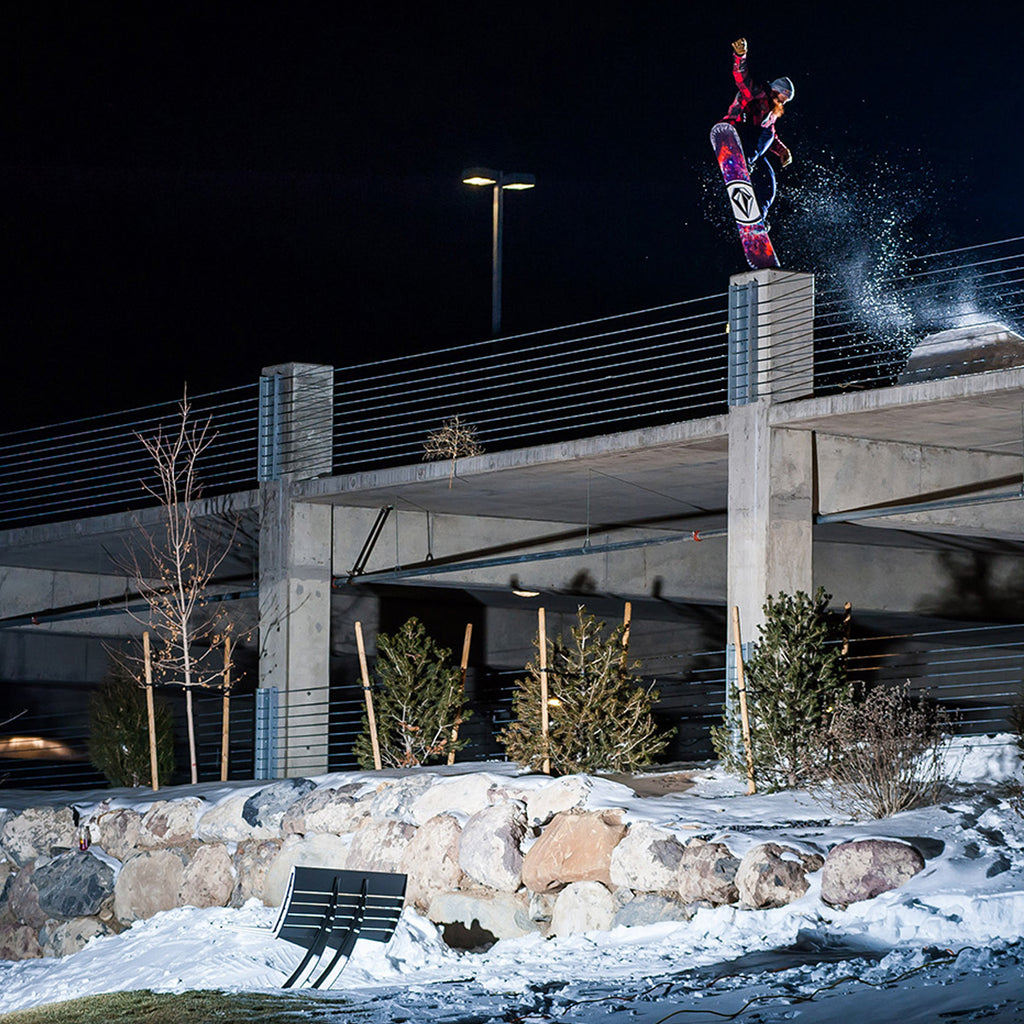 Night shot of Pat Moore jibbing off a parking building on his snowboard.