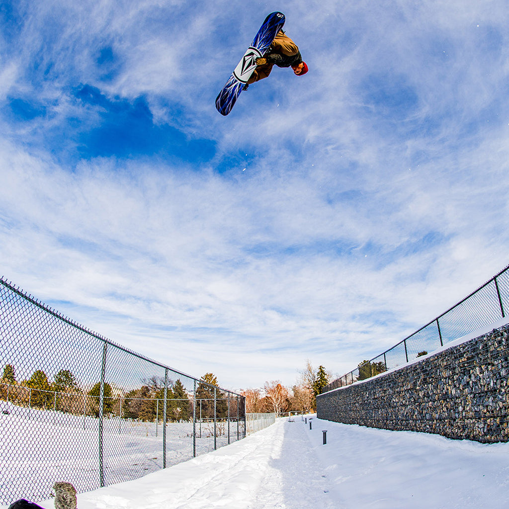 Pat Moore doing a big indi spin on his snowboard over two fences.