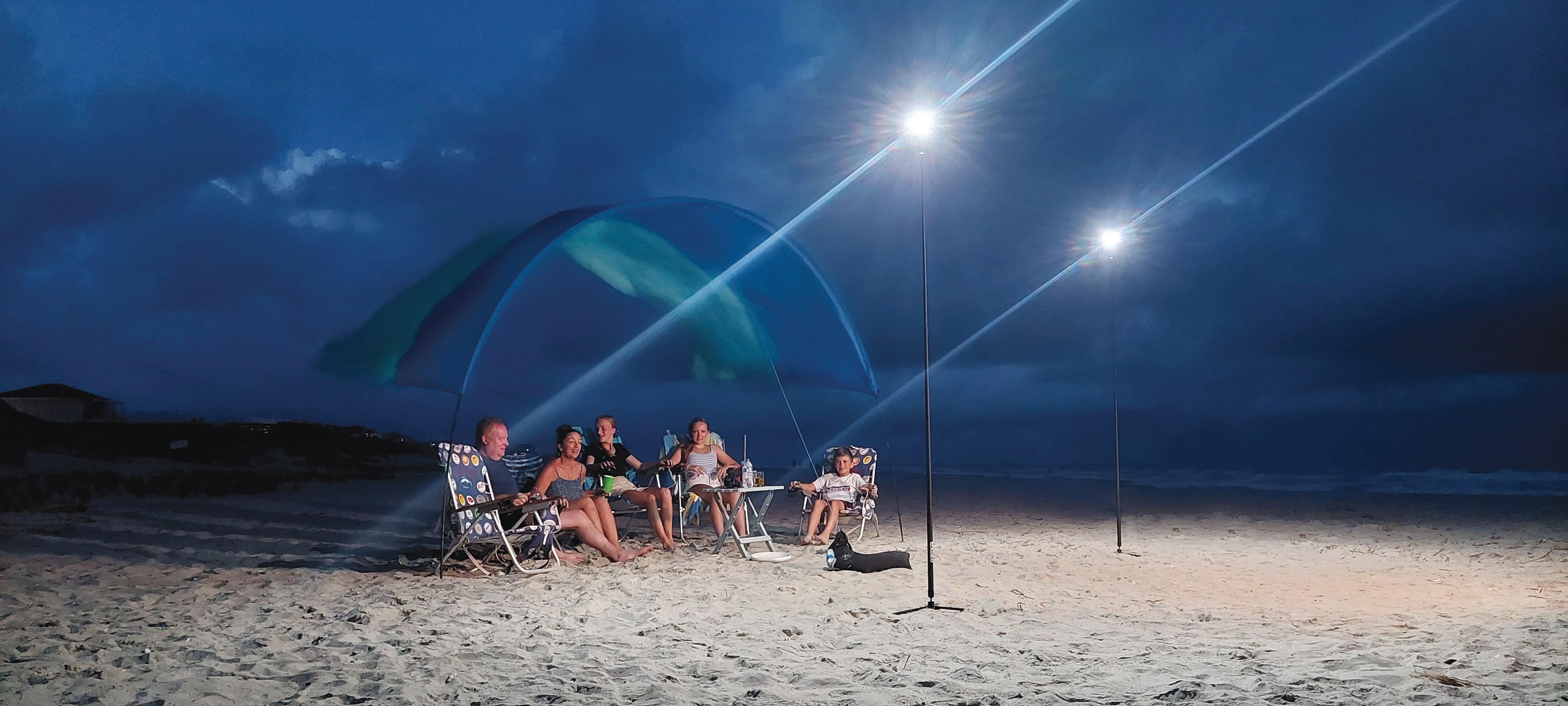 a family sitting on the beach at night illuminated by 2 FLi Telescoping lights by STKR