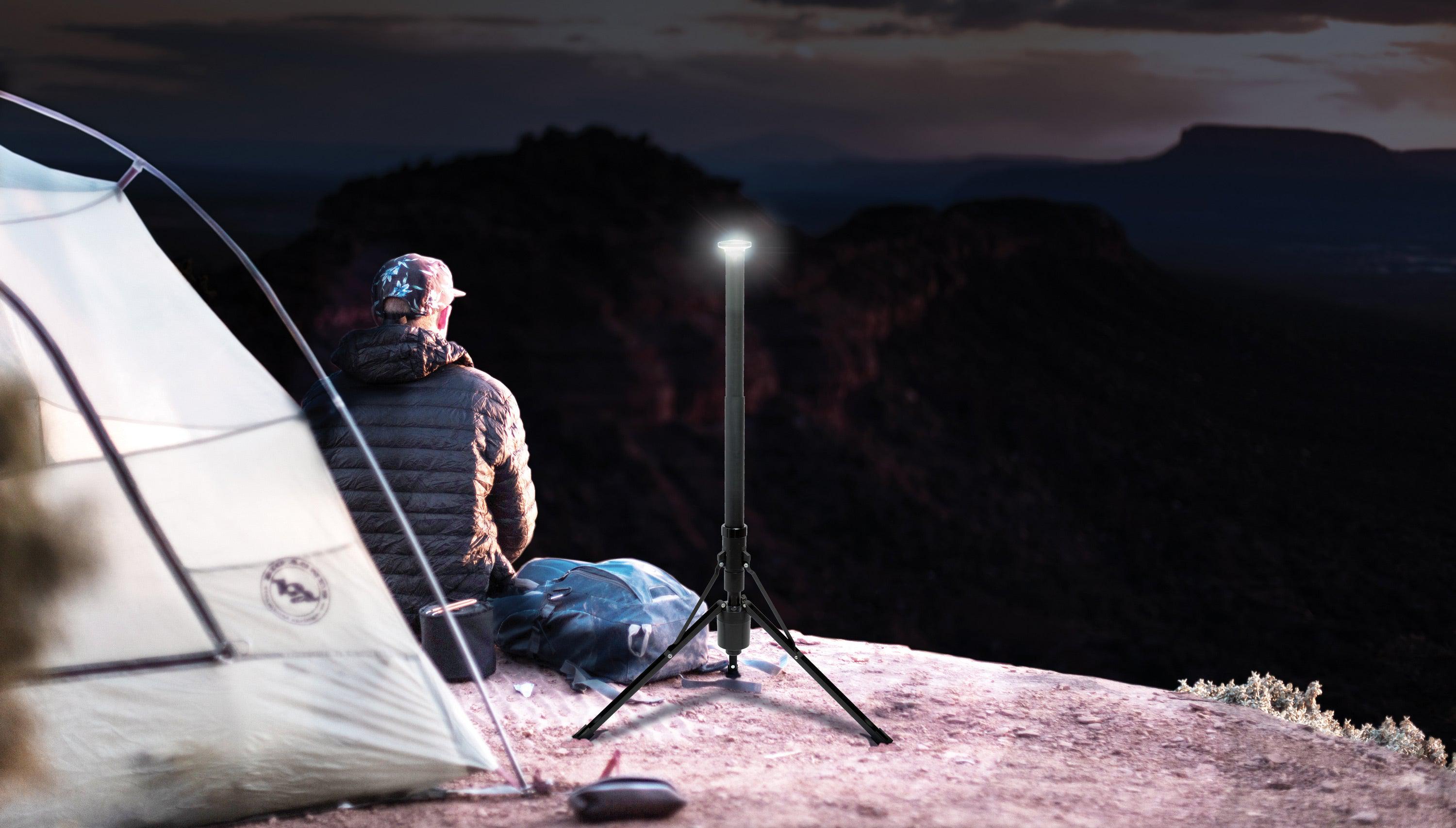 Male sitting on a mountainside overlooking mountains in the distance. He's surrounded by a tent and a FLi Over-Lander.