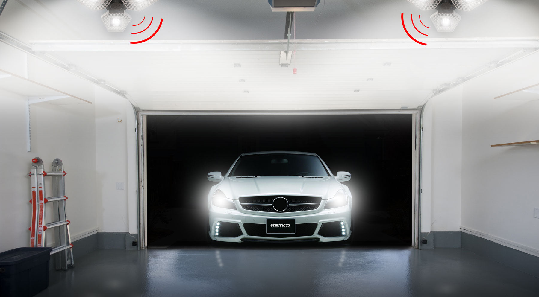 clean garage with two TRiLIGHTs. Red graphics depicting the lights 'sensing' the car that has just started to enter.